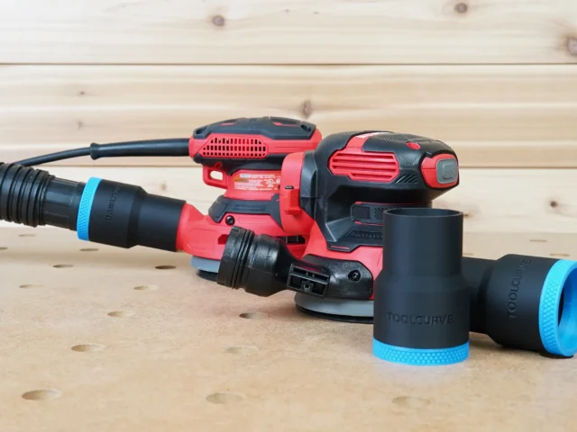Black 1-7/8 inch ToolCurve hose adapter with blue ring connecting a vacuum hose to a Craftsman sander, plus two spare adapters