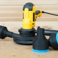 Black ToolCurve 2-1/2" hose adapters with blue trim beside a yellow Dewalt disc sander on a workbench