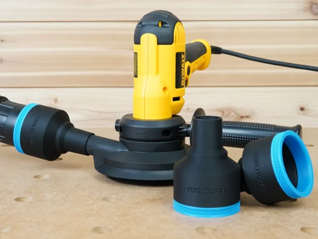 Black ToolCurve 2-1/2" hose adapters with blue trim beside a yellow Dewalt disc sander on a workbench