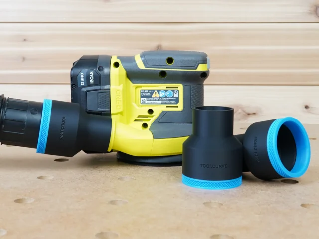 Black 2-1/2 inch ToolCurve hose adapter connecting a vacuum hose to a Ryobi 18v sander, with two spare adapters beside it