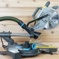 Black 36mm hose adapter with blue band joining a dust hose to a Ryobi 10-inch sliding miter saw, spare adapter on the table