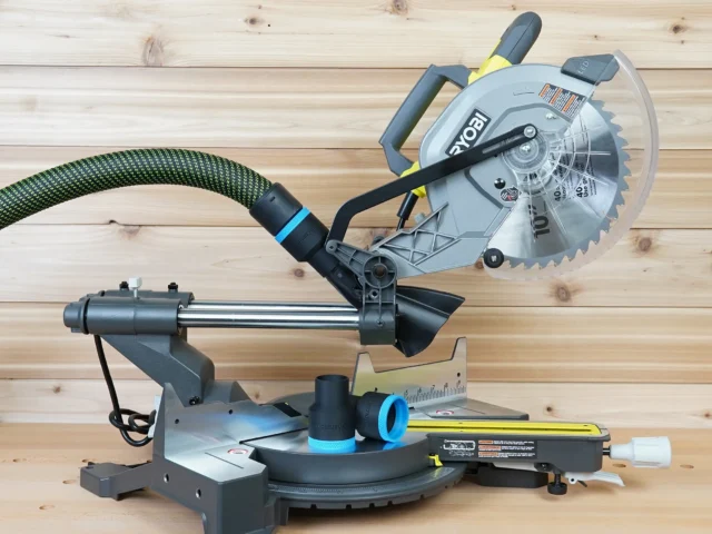Black 36mm hose adapter with blue band joining a dust hose to a Ryobi 10-inch sliding miter saw, spare adapter on the table