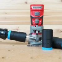 Black 1-1/4 inch hose adapter with blue collar joining an orange vacuum hose to a red Craftsman 20v router, plus two spare adapters