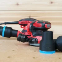 Black ToolCurve 2-1/2" hose adapter with blue trim beside a red Craftsman sander connected to a vacuum hose