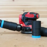 Black hose adapter with blue bands attached to Craftsman random-orbit sander dust port, showing compatible 27mm hose connections