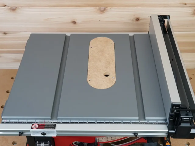 Zero clearance insert installed on Milwaukee M18 table saw, showing rounded MDF insert plate with center opening and mounting screws