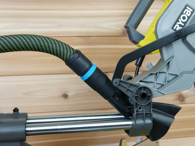 Hose adapter with blue band attached to Ryobi 10-inch sliding miter saw dust port, connected to green and black hose