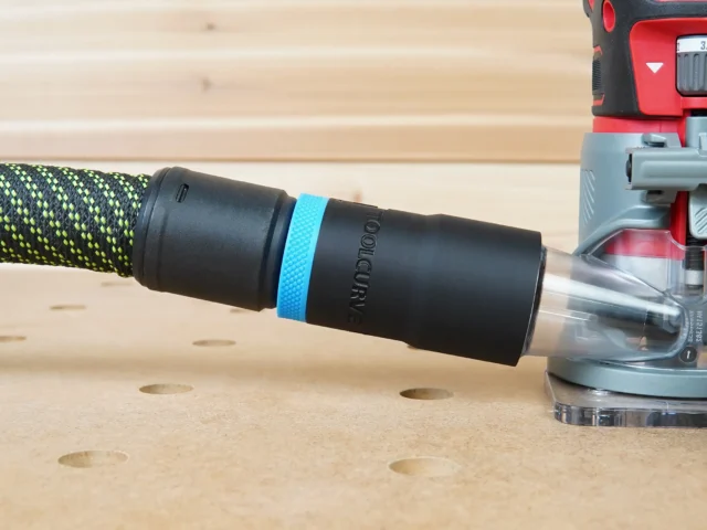 Black hose adapter with blue band attached to braided Festool hose next to Craftsman 20v router on wood workbench
