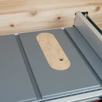 Zero clearance insert for Milwaukee M18 table saw, installed in saw with tan MDF face and center opening, flanked by gray aluminum wings
