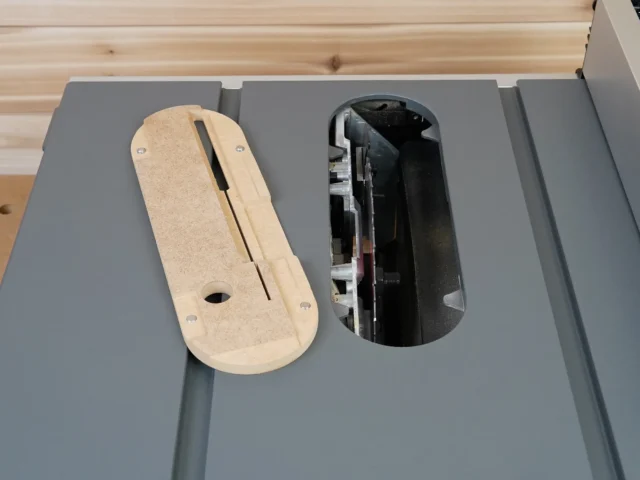 Zero Clearance insert for Milwaukee M18 table saw, made from light MDF with a center slot, shown installed next to the standard black insert