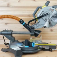 Black 1-1/4 inch hose adapter with blue band linking an orange vacuum hose to a Ryobi 10-inch sliding miter saw dust port