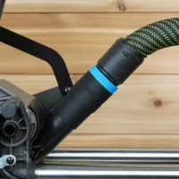 Black hose adapter with blue band attached to Ryobi 10-inch miter saw dust port, connected to green and black braided hose