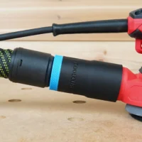 Black hose adapter with blue band attached to Craftsman orbital sander dust port, connected to green and black braided hose