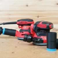 Black 1-1/4" ToolCurve hose adapter with blue collar joining an orange hose to a Craftsman sander, two spares beside