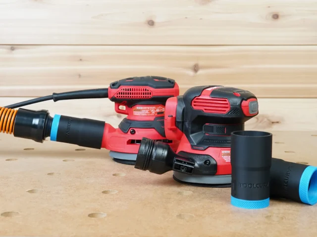 Black 1-1/4" ToolCurve hose adapter with blue collar joining an orange hose to a Craftsman sander, two spares beside