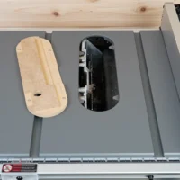 Zero clearance insert for Milwaukee M18 table saw installed in saw top, with wooden insert visible on left and open cutout showing blade area on right