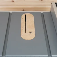 Zero clearance insert for Milwaukee M18 table saw installed on saw table, showing rounded wood shape with vertical slot and offset hole for blade height adjustment