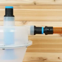 Two black ToolCurve 1-1/4 inch hose adapters with blue rings on a Cen-Tec Quick-Click separator, one joined to an orange hose