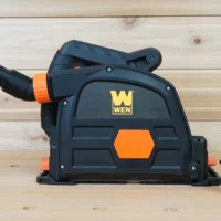Black plastic no snag dust port adapter attached to Wen track saw, with orange hose connector angled upward and separate hose end port shown alongside