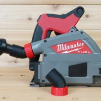 No Snag Dust Port for Milwaukee track saw attached to gray and red Milwaukee FUEL circular saw, showing angled black hose adapter with yellow flex hose connected