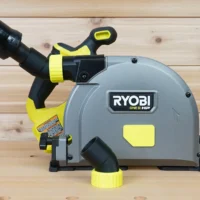 No Snag Dust Port for Ryobi track saw attached to a gray and yellow Ryobi saw, with orange hose routed upward away from the track
