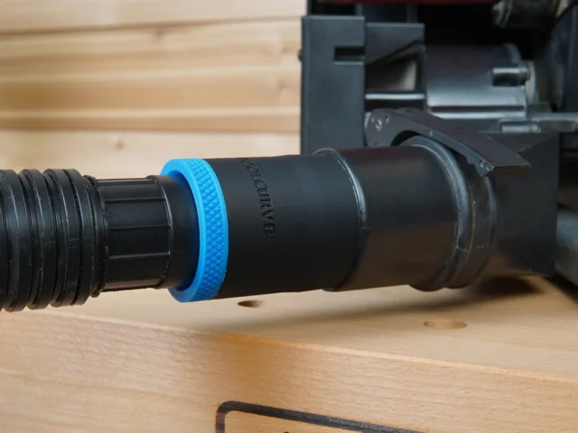 Black 1-7/8 inch hose adapter with blue ring joining a vacuum hose to a Porter Cable benchtop sander dust port