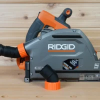 ToolCurve no snag dust port mounted on a Ridgid track saw, angling hose upward with orange and gray body