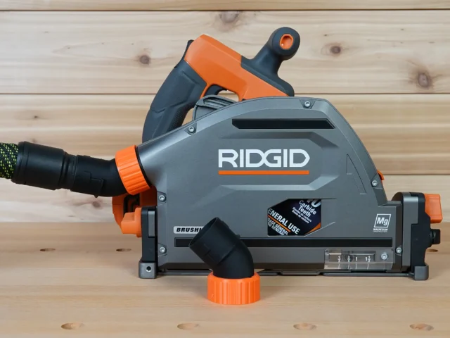 ToolCurve no snag dust port mounted on a Ridgid track saw, angling hose upward with orange and gray body