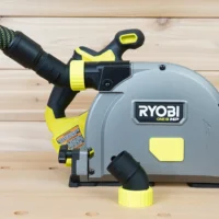 Black and yellow no snag dust port adapter mounted on a Ryobi track saw, with hose attached angled upward from the port