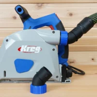 No Snag Dust Port for Kreg track saw with angled hose outlet, shown installed on a Kreg saw with blue trim detail and vacuum hose attached