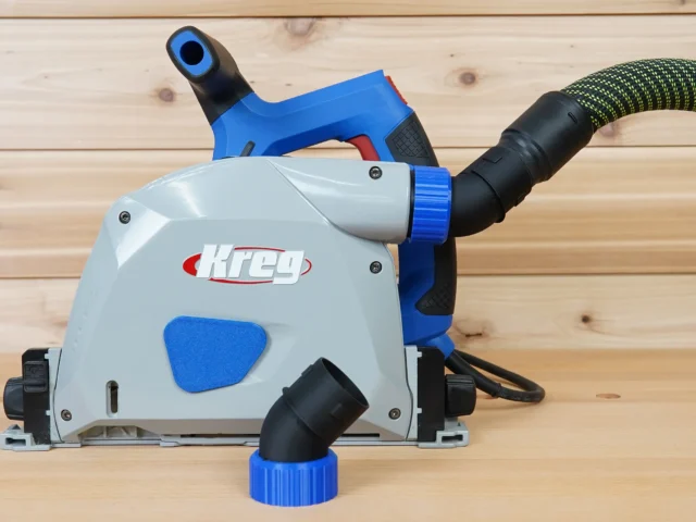 No Snag Dust Port for Kreg track saw with angled hose outlet, shown installed on a Kreg saw with blue trim detail and vacuum hose attached