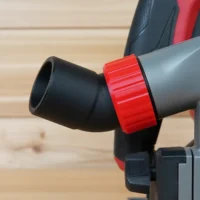 Black no snag dust port with red collar attached to Milwaukee track saw, angled upward away from the workpiece