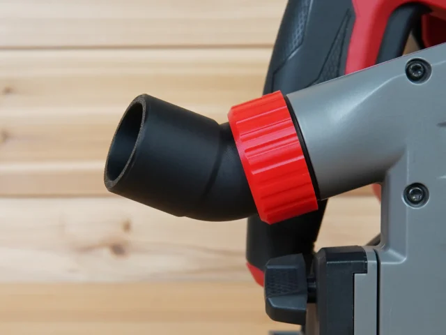 Black no snag dust port with red collar attached to Milwaukee track saw, angled upward away from the workpiece