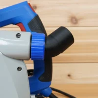 Blue and black no snag dust port adapter mounted on a Kreg track saw, with hose angled upward away from the saw