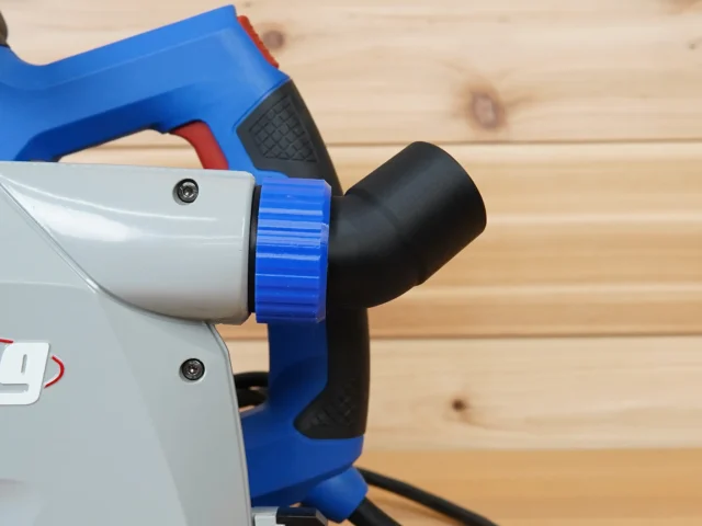 Blue and black no snag dust port adapter mounted on a Kreg track saw, with hose angled upward away from the saw
