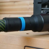 ToolCurve hose adapter with blue band attached to green-and-black braided hose, connected to Porter Cable benchtop sander dust port
