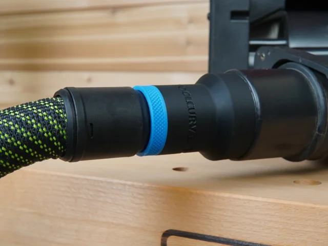 ToolCurve hose adapter with blue band attached to green-and-black braided hose, connected to Porter Cable benchtop sander dust port