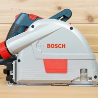 Bosch GKT13 corded track saw shown from the side with a red arbor cover fitted flush on the blade housing