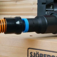 Black 1-1/4 inch hose adapter with blue collar joining an orange vac hose to a Porter Cable sander dust port