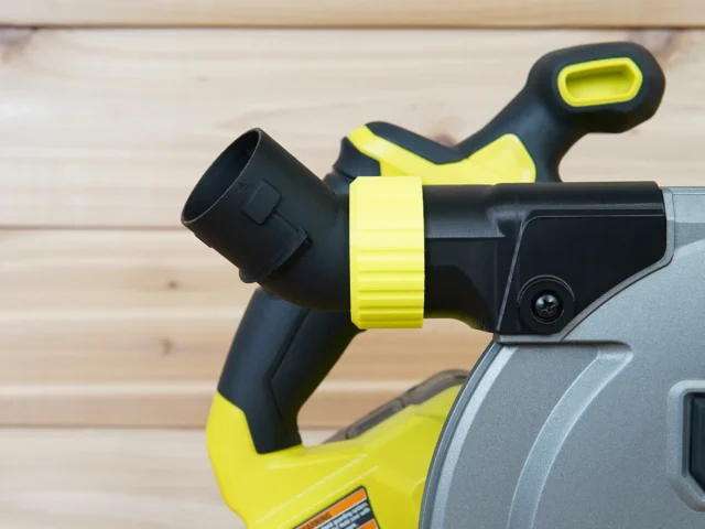 Black and neon-yellow dust port adapter mounted on a Ryobi track saw, with hose collar angled upward and away from the tool