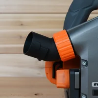 No Snag Dust Port for Ridgid Track Saw attached to gray track saw body, orange adapter angled upward with black hose connector