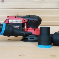Black ToolCurve 1-7/8 inch hose adapter with blue cuff connecting a vac hose to a Milwaukee M18 sander, plus two spare adapters