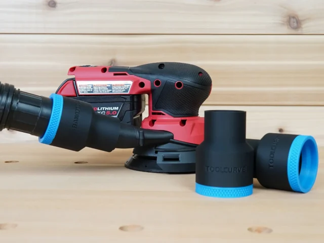 Black ToolCurve 1-7/8 inch hose adapter with blue cuff connecting a vac hose to a Milwaukee M18 sander, plus two spare adapters