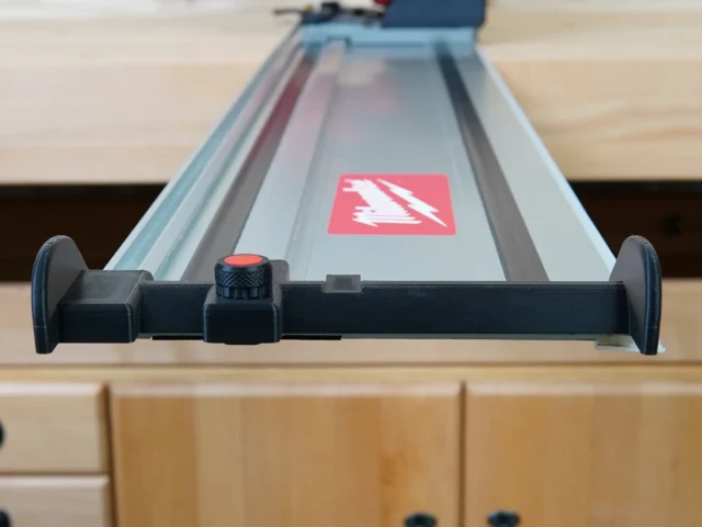 Black hose deflector with red knob mounted on Milwaukee guide rail with ToolCurve branding visible on rail surface