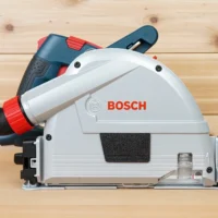White arbor cover attached to Bosch track saw, showing snap-on design and dust collection enclosure