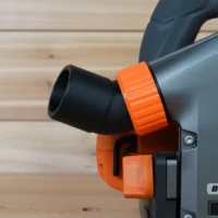 Black and orange no-snag dust port adapter attached to a Ridgid track saw, with hose angled upward away from the tool