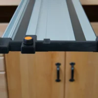 Black hose deflector mounted on PowerTec guide rail with orange quick-release knob and dual clamping handles