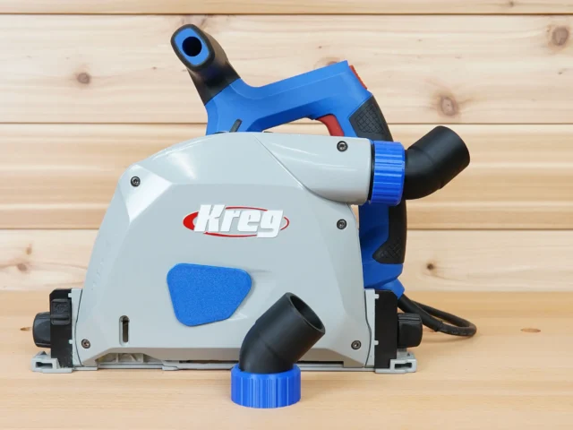 No Snag Dust Port for Kreg track saw shown attached to a Kreg track saw, with blue and black hose adapter angled upward away from the tool base