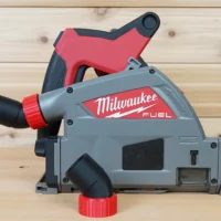 No Snag Dust Port for Milwaukee track saw mounted on a Milwaukee M18 track saw, angling the hose upward with red and black plastic components