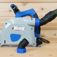No snag dust port adapter mounted on a Kreg track saw, with hose angled upward and detachable blue coupling visible below